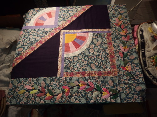 A corner of the Woollen PNG quilt with leaf borders lying beside it.  