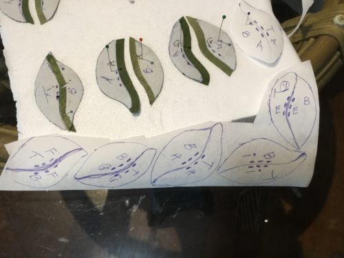 First I traced all the leaf shapes on to the washaway freezer paper, numbered them , T for top of the leaf B for bottom, then added letters telling which one went where on the bouquet on both 1/2s. Last was a mark of 3 dots on each 1/2 where I was going to cut the leaf in 1/2 so I knew at a glance they were the middle join, when you have lots of 1/2 leaves it saves a lot of time? 
